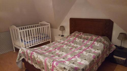 a bedroom with a crib and a bed with a blanket at Le rossignol in Coigneux