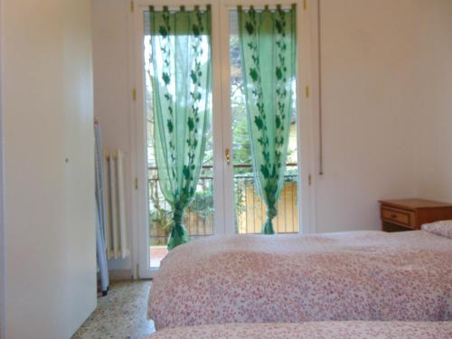 a bedroom with a bed and a window with green curtains at Mi.Ma's dream in Milano Marittima
