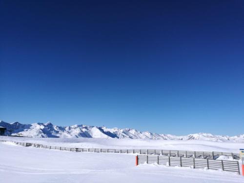 a fence in the snow with mountains in the background at Ferienwohnung Holzer in Sankt Michael im Lungau