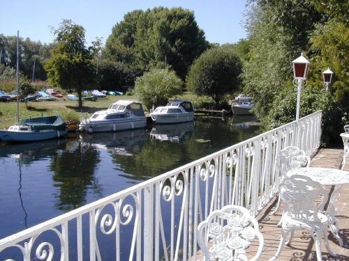 a deck with chairs and boats in a river at Warren Lodge in Shepperton