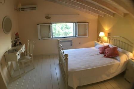 a bedroom with a large white bed with a window at Villa Costa Hydra in Plépi