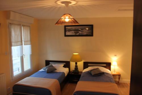 2 camas en una habitación con lámpara y ventana en La Margot'ine, en Montrieux-en-Sologne