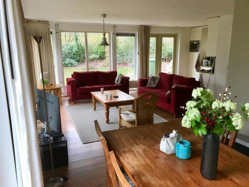 a living room with a table and red furniture at Vakantiewoning Tjiftjaf in "Het Fonteinbos" in Oudemirdum