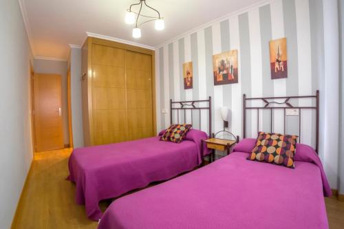 two beds in a room with purple sheets at Apartamento Sella y Mar - VUT12AS in Ribadesella