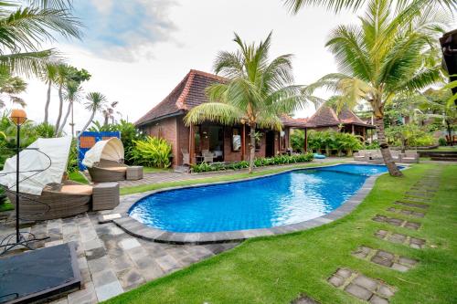 a swimming pool in front of a house with palm trees at Arton Resort & Beach Club in Pulukan