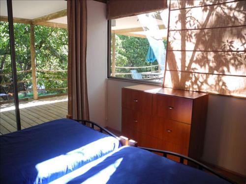 a bedroom with a bed and a dresser and a window at Cabañas Nogalia in San Alfonso