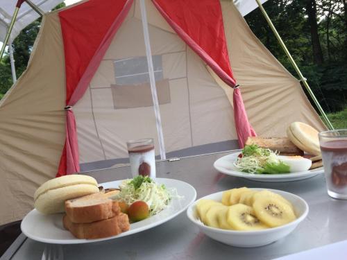 drei Teller Essen auf einem Tisch vor einem Zelt in der Unterkunft Yado Brodiaea in Myōkō