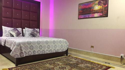 a bedroom with a bed with a purple wall at Hotel Seven 7 in Karachi