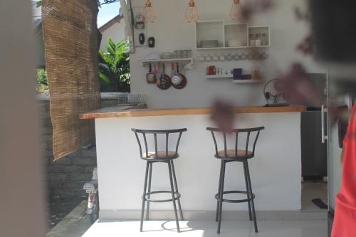 a kitchen with two bar stools at a counter at Casa Blanca Gili Air in Gili Air