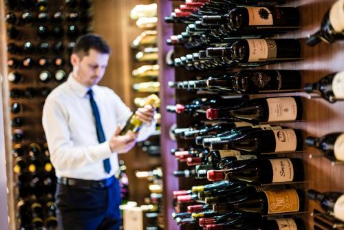 a man standing in front of a wall of wine bottles at Sweet Hotel in Longa