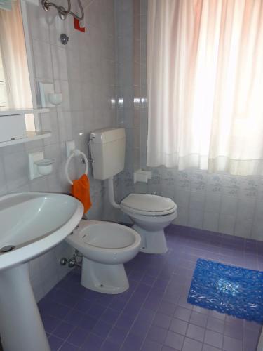 a bathroom with a white toilet and a sink at Gabbiano - Appartamenti in Bibione