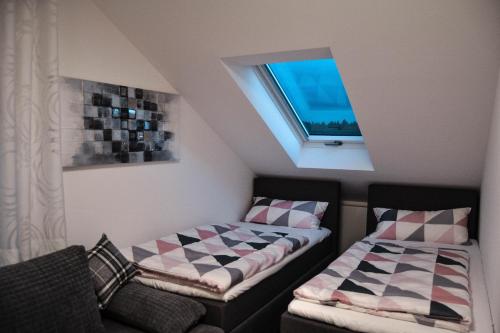 EgloffsteinにあるTannenblick-Frankenのベッド2台と窓が備わる屋根裏部屋です。