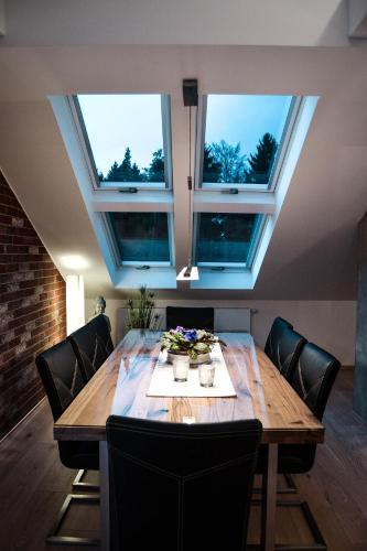a dining room with a table with chairs and two windows at Tannenblick-Franken in Egloffstein