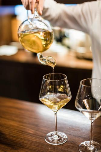 a person pouring white wine into two wine glasses at Sweet Hotel in Longa