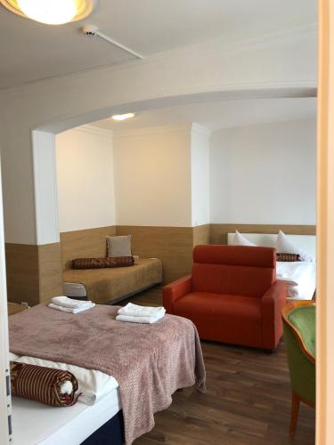 a room with a bed and a red chair at Hotel Vogelweiderhof in Salzburg