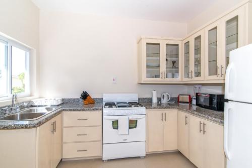 eine Küche mit weißen Geräten und einem weißen Kühlschrank in der Unterkunft Luxury 2BR Home facing Beach w/Pool Montego Bay #5 in Montego Bay
