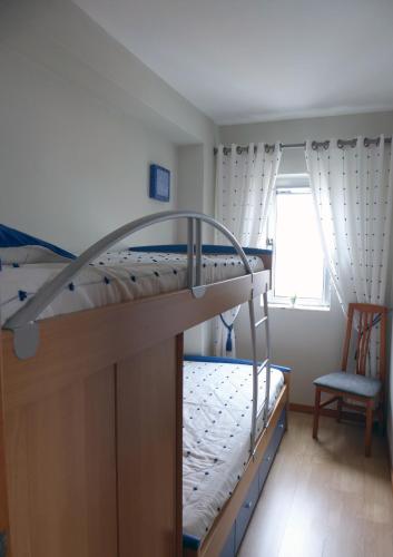 a bedroom with a bunk bed and a chair at Near Beach Apartment in Póvoa de Varzim
