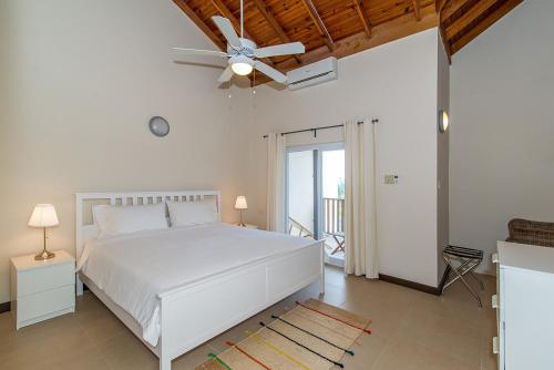a bedroom with a white bed and a ceiling fan at Family Complex beside Beach w/Pool Montego Bay #2 in Montego Bay