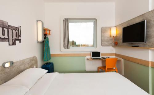 a bedroom with a bed and a desk and a tv at ibis budget Campinas Aquidaban in Campinas