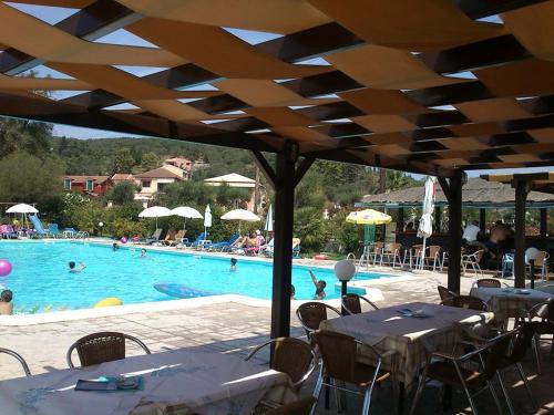 a pool with tables and chairs and people in the water at Egrypos Hotel in Petrití