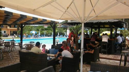 a group of people sitting at a restaurant under an umbrella at Egrypos Hotel in Petrití