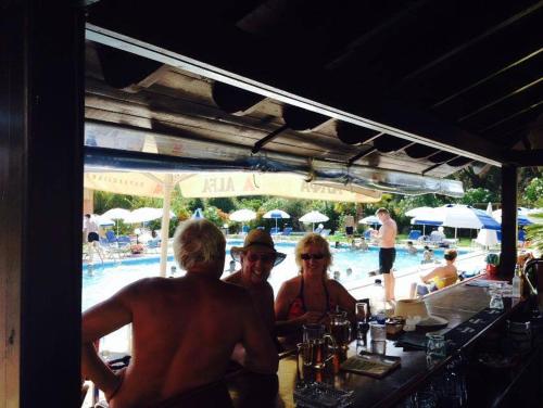 a group of people sitting at a bar near a pool at Egrypos Hotel in Petrití
