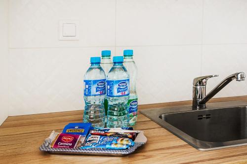 two bottles of water and chips next to a sink at Apartament Kniaziewicza - Komfortowe Noclegi in Piaseczno