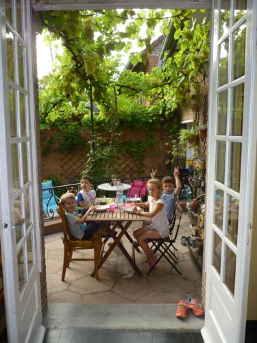 een groep kinderen aan een tafel op een patio bij au vieux cèdre in Mouvaux