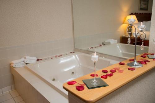 uma casa de banho com banheira e uma mesa com rosas em The Carlton Lodge em Adrian