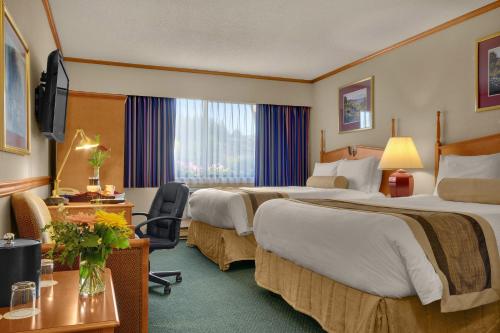 um quarto de hotel com duas camas e uma secretária em The Hospitality Inn em Port Alberni