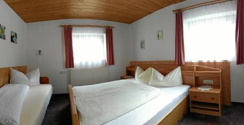 una camera da letto con due letti e due finestre di Haus Rosi a Sankt Leonhard im Pitztal