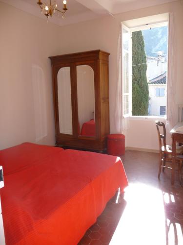 une chambre avec un lit rouge et une grande fenêtre dans l'établissement Maison Daumas Billard Français et Piscine, à Robion