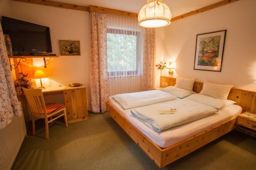 a bedroom with a bed and a desk and a television at Haus Petersmann in Ramsau am Dachstein