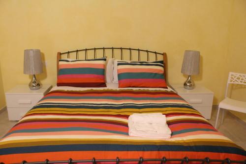 a bed with a colorful striped blanket and two lamps at Casetta di Arcangelo in Cisternino