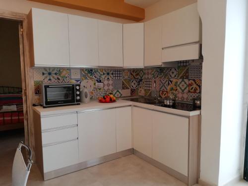 a kitchen with white cabinets and a microwave at Casetta di Arcangelo in Cisternino