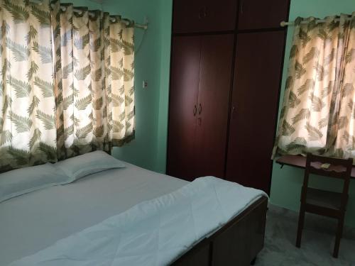 a bedroom with a bed and curtains and a chair at Nalanda Tulip in Kolkata