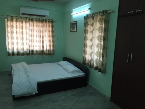 a small bedroom with a bed and two windows at Nalanda Tulip in Kolkata