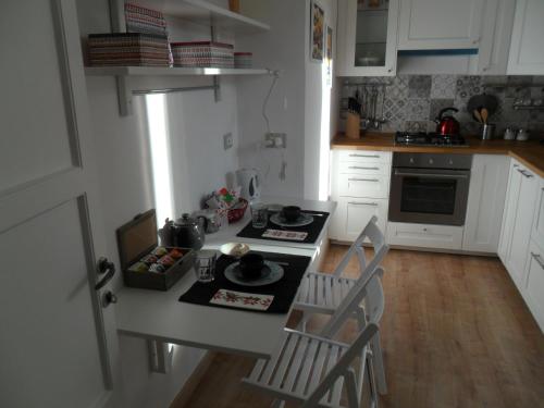 a kitchen with white cabinets and a table with chairs at Casa della nonna sulla francigena in Campagnano di Roma
