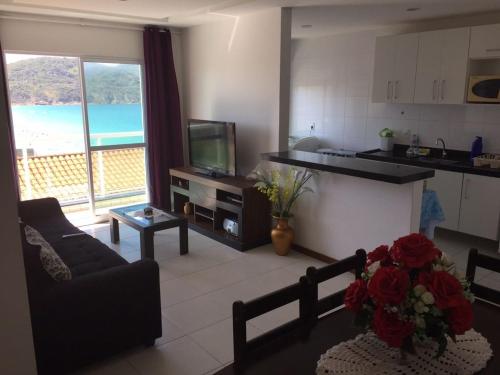 sala de estar con sofá y cocina con TV en Condomínio Beach Town., en Arraial do Cabo