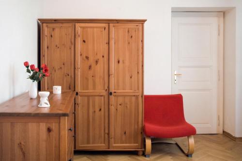 uma cadeira vermelha sentada ao lado de um armário de madeira em Ai Quattro Angeli em Praga
