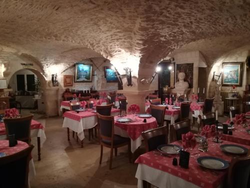 a restaurant with red tables and chairs in a tunnel at Hostellerie Saint Martin- Logis Hôtel et Restaurant in Creully
