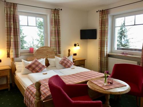 une chambre d'hôtel avec un lit, une table et deux fenêtres dans l'établissement Gästehaus Tanneck, à Reit im Winkl