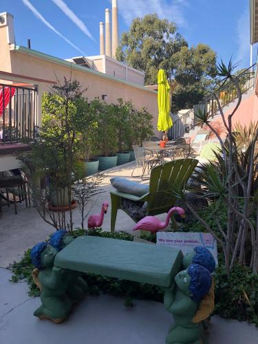 a garden with a green bench and pink birds at Bayfront Inn in Morro Bay