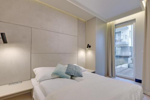 a bedroom with a white bed and a window at INA Rent - Tre Mare Apartamenty in Gdańsk