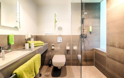 a bathroom with a toilet and a glass shower at Hotel Carolinenhof in Berlin