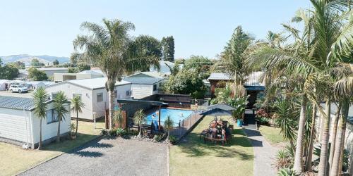 una vista aérea de una casa con piscina y palmeras en Mercury Bay Holiday Park, en Whitianga