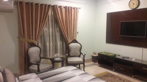 a bedroom with two chairs and a tv and a bed at Hotel Seven 7 in Karachi