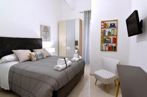 サレルノにあるGemini Suiteのベッドルーム(ベッド1台、テレビ、椅子付)
