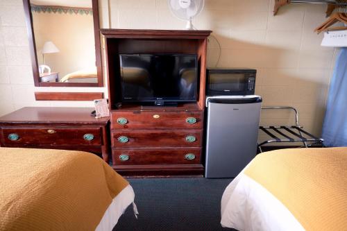 リベラルにあるSouth Wind Innのベッド2台、テレビ、ドレッサーが備わる客室です。