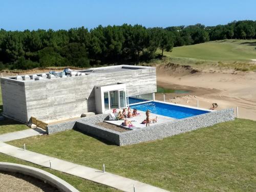 een huis met een zwembad naast een strand bij Costa Esmeralda Departamento para 6 Personas sobre el Golf in Pinamar